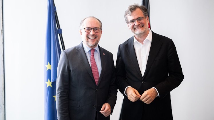 Außenminister Schallenberg mit dem Deutsch Kanzleramtsminister Schmidt, stehend vor der europäischen und der deutschen Fahne.