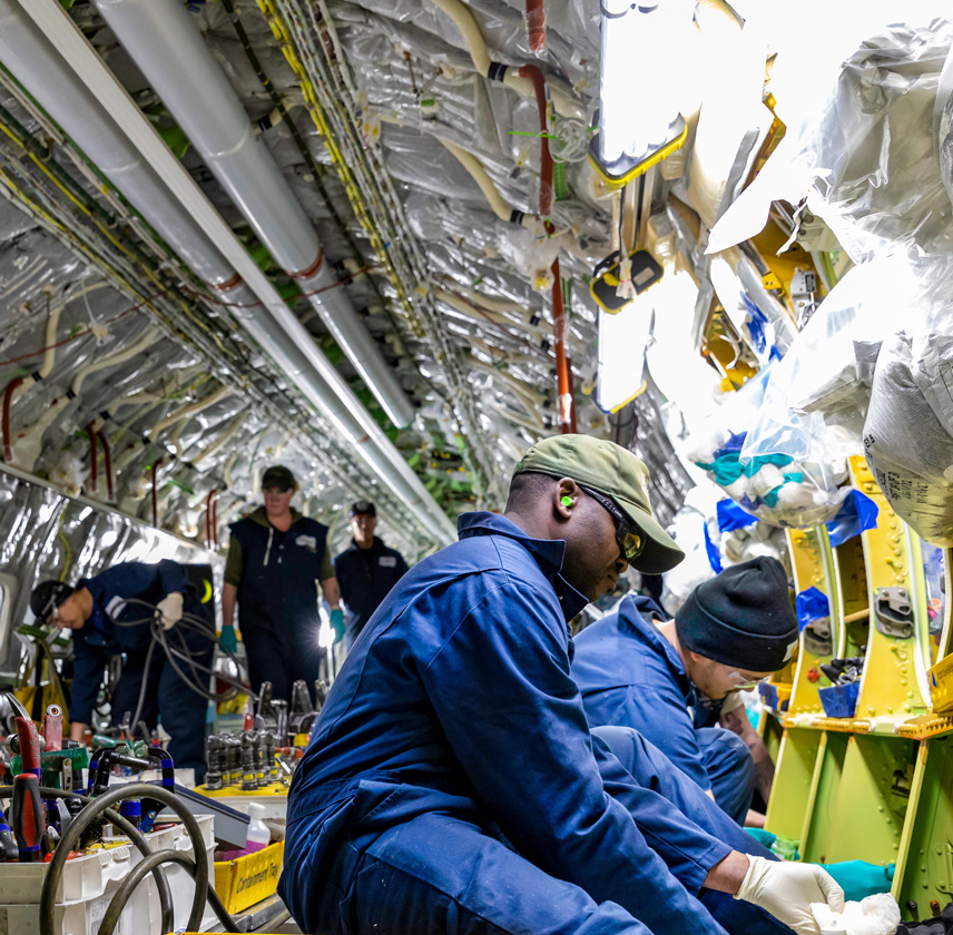 Employees performing work inside of airplane.