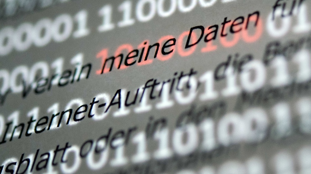 Der Abschnitt "meine Daten" einer Musterdatenschutzerklärung wird von roten Einsen und Nullen hervorgehoben, die auf einem Bildschirm hinter dem Papier zu sehen sind. | Bild: dpa-Bildfunk/Sebastian Gollnow