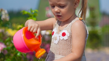 Ein Mädchen gießt aus einer Plastik-Gießkanner Wasser in ihre Hand. | Bild: colourbox.com