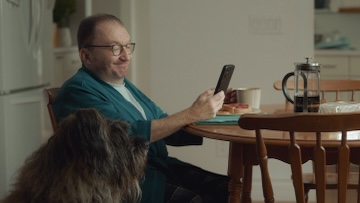 A man sitting down, looking at his phone.