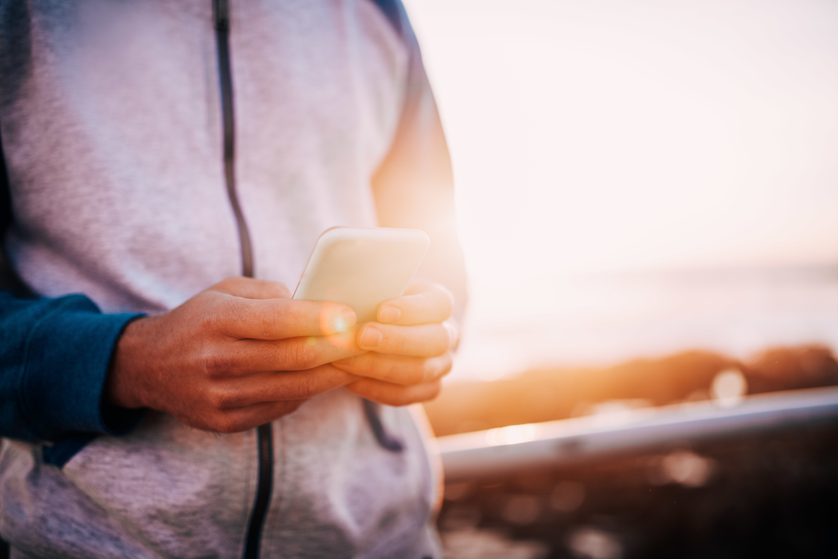 white male holding cell phone while standing outside