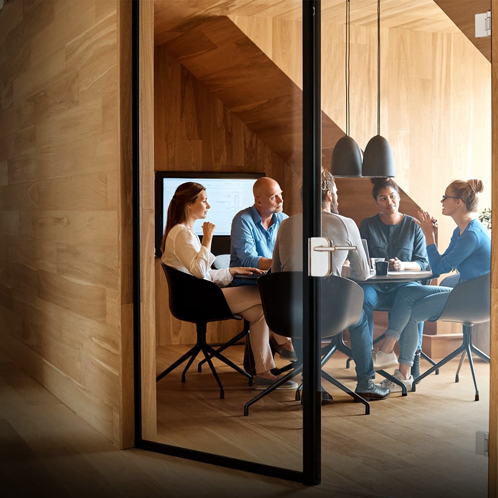 Group of office colleagues sit around a meeting table.