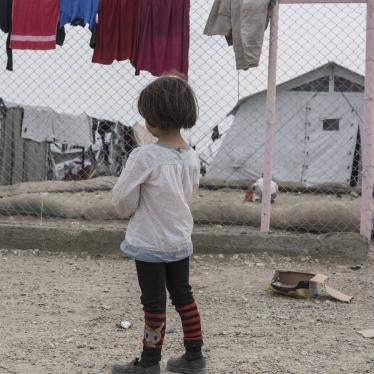 A girl stands in front of a chainlink fence