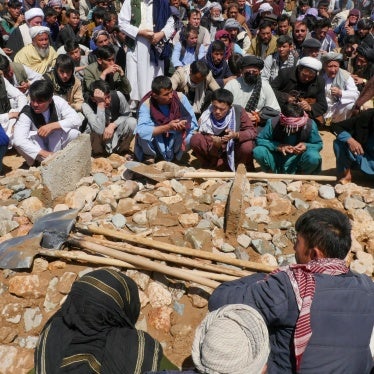 A crowd surrounds a burial site