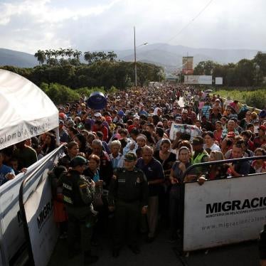 Colombian police officers stand in front of people queueing to try to cross into Colombia from Venezuela through the Simon Bolivar international bridge in Cucuta, Colombia. January 24, 2018.