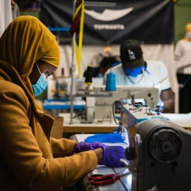 A woman from Barcelona’s street vendors union sews protective face masks for the use of health care workers whose supplies are running low, March 2020