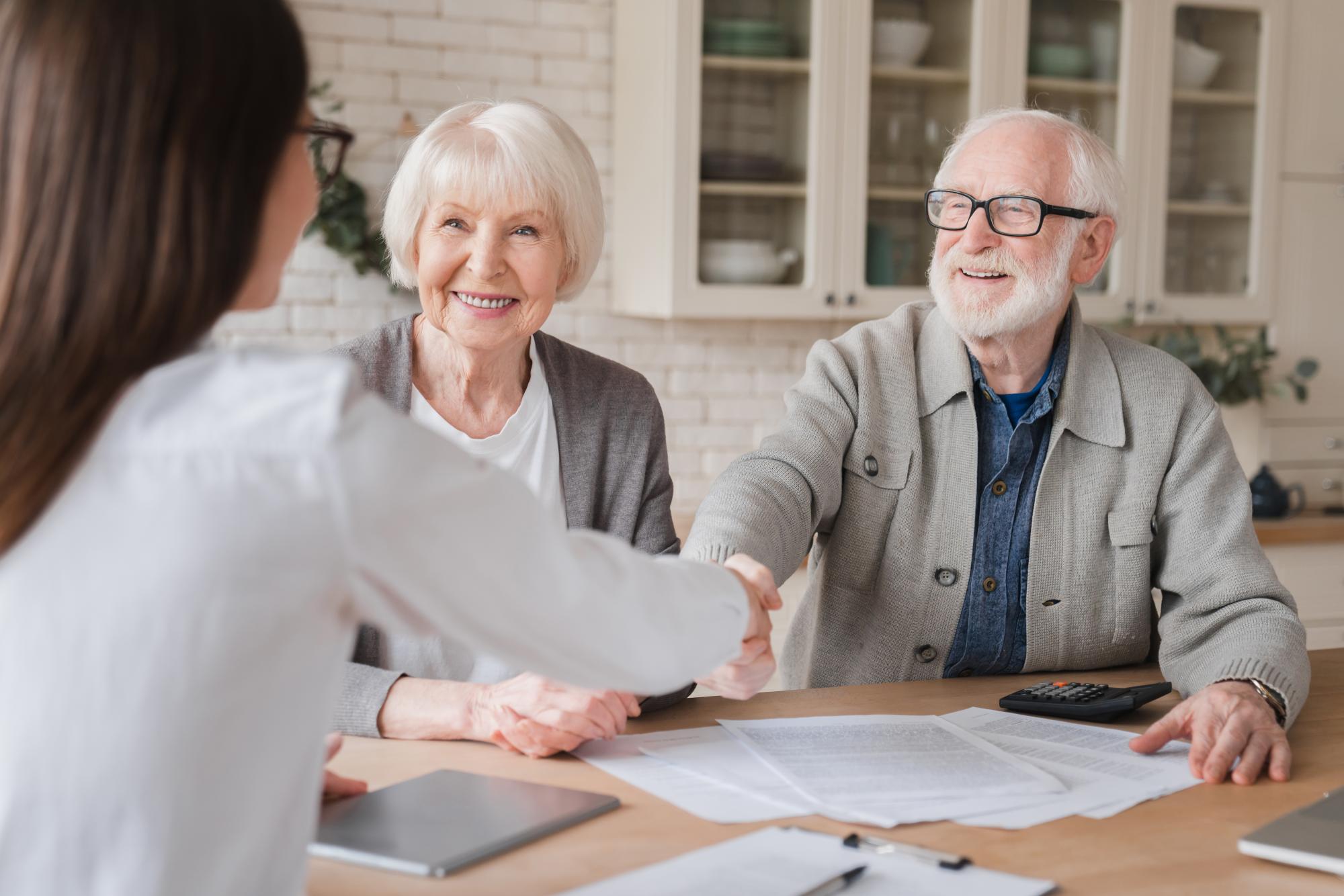 Senior couple shaking hands closing on a loan