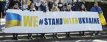 Demonstration, people holding banner saying "We stand with Ukraine"