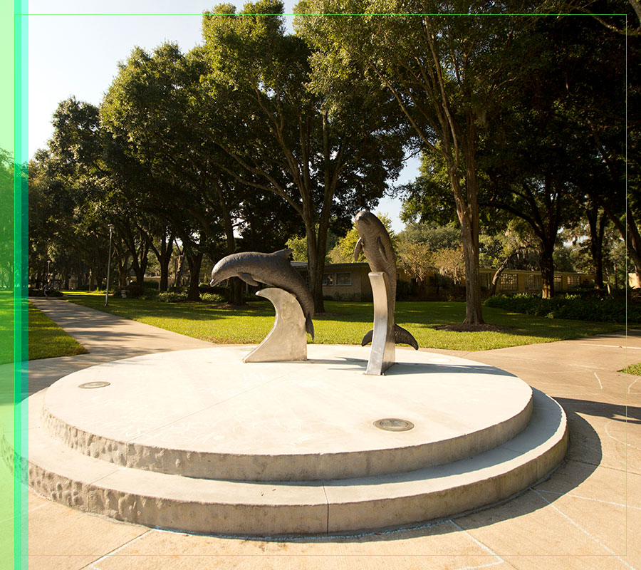 A sunlit picture of the dolphin statues behind the Howard Administration Building.