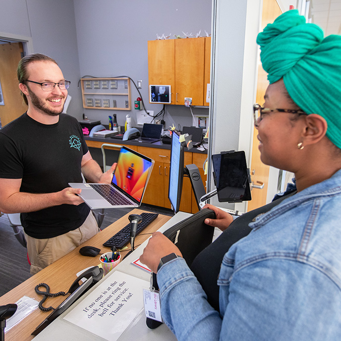 Tech Lending worker giving student a laptop