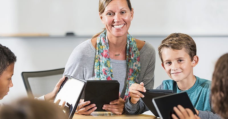 Lehrerin mit Schülern und Tablets