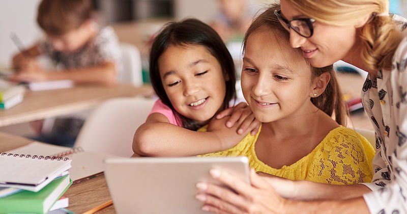 Lehrerin mit Grundschülerinnen am Tablet