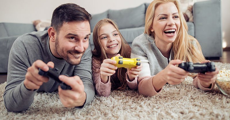 Familie liegt auf dem Boden und halten Game-Controller in den Händen