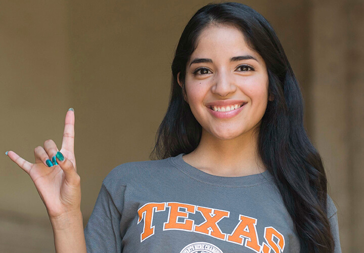 Smiling student gives hook em horns