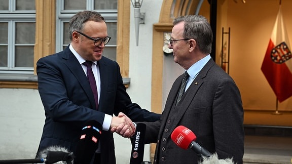 Der neu gewählte Ministerpräsident Mario Voigt (CDU, l) und der frühere Ministerpräsident Bodo Ramelow (Die Linke) geben sich vor der Staatskanzlei die Hand.