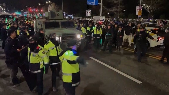 Ein Militärfahrzeug wird von Passanten behindert.