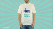 Ein Mann hat ein weißes T-Shirt an, auf dem in blauer Schrift "NDR 1 Radio MV Trikottausch" steht. © Screenshot 