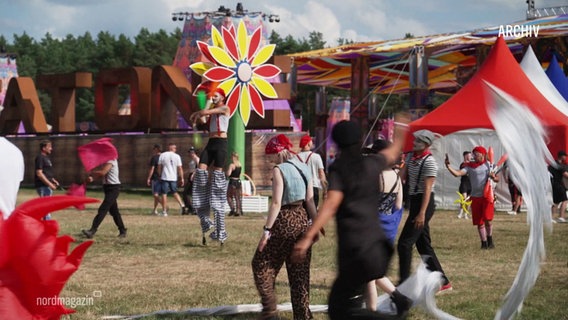 Besucher in bunter Kleidung feiern auf dem Air Beat One Festival. © Screenshot 