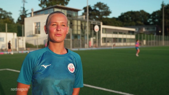 Eine junge Frau im blauen Trikot steht auf einem Fußballplatz. © Screenshot 