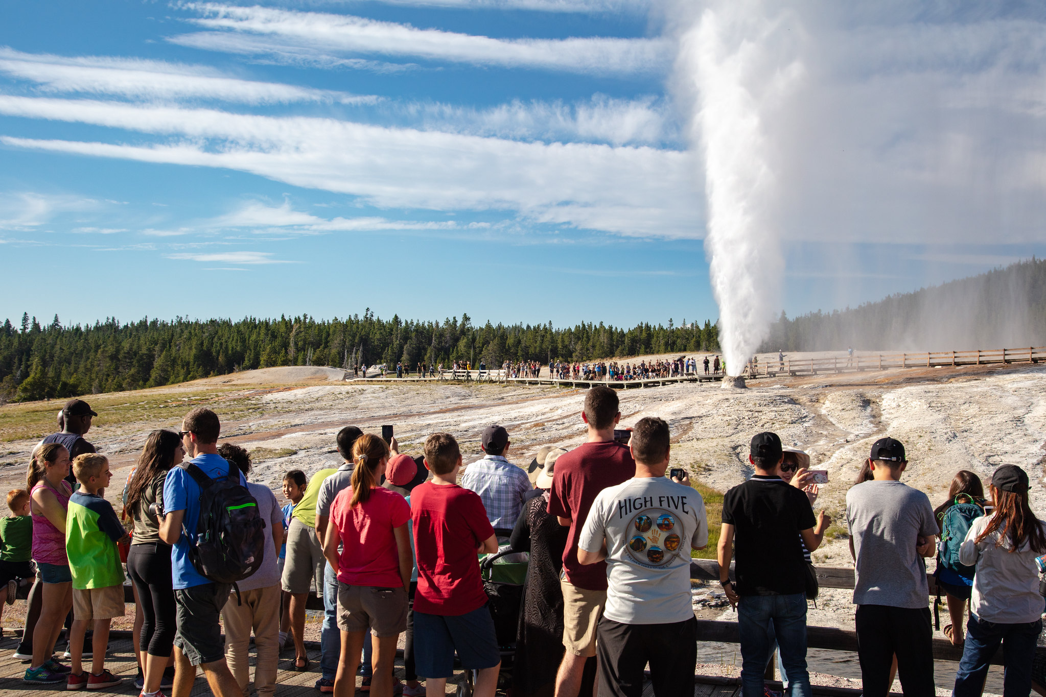 a crowd of people watching a geyser erupt