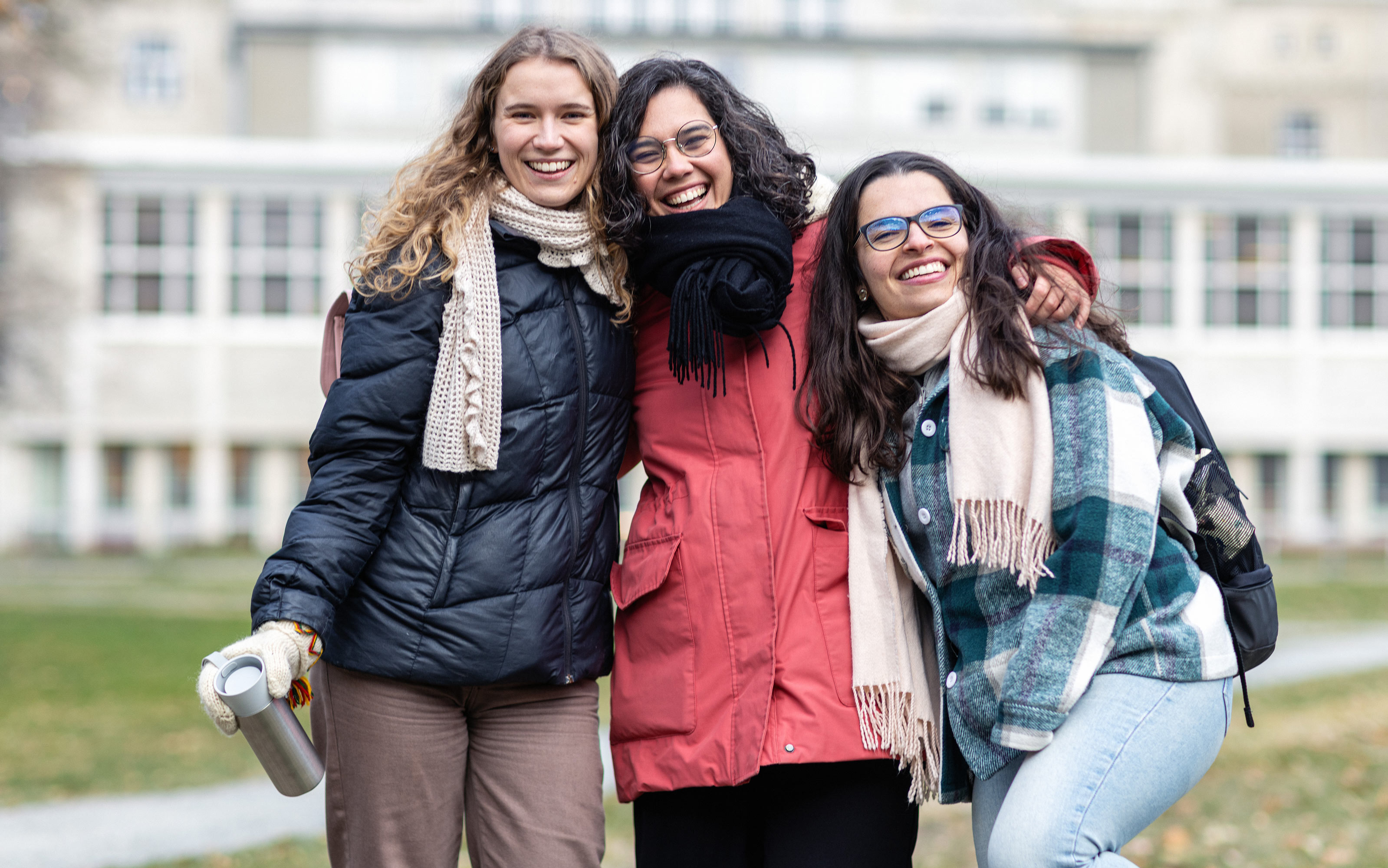 Three smiling students, on campus. Photo.