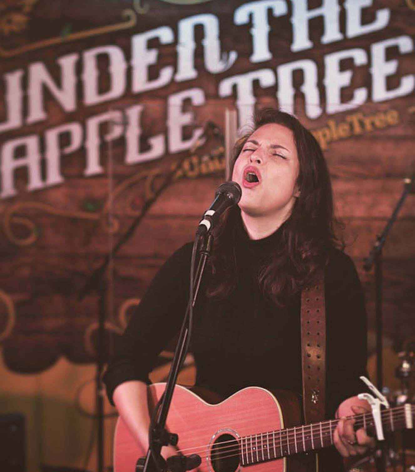 Danni Nicholls singing and playing acoustic guitar