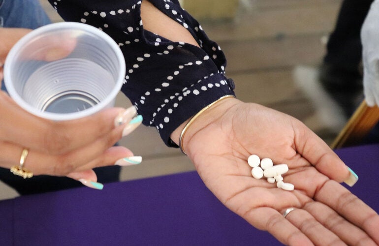 Treatment for lymphatic filariasis. Woman hold pills on her hand.