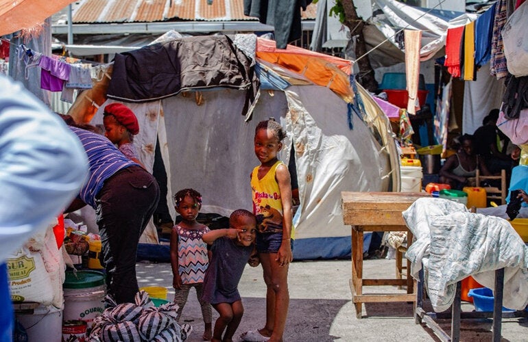 Niños sonríen a la cámara en un campamento en Haití