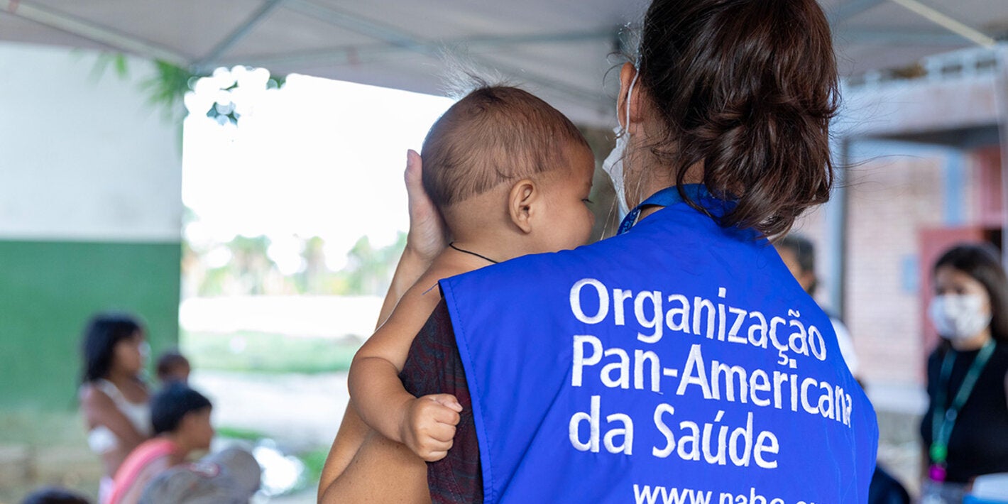 Consultora de la OPS sostiene a niño indígena en sus brazos