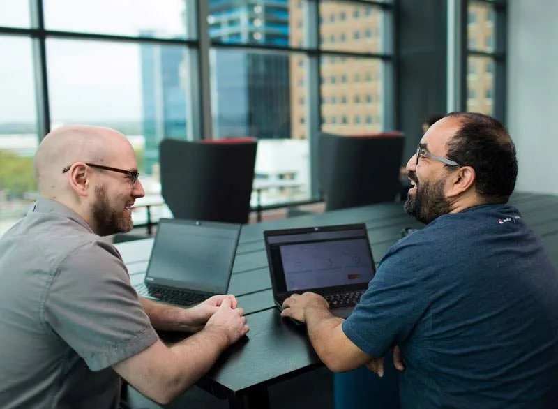 2 men speaking while at a computer