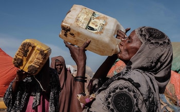 Mohamed Isack (R), 60, drinks water at a water distribution point at Muuri camp, one of the 500 camps for internally displaced persons (IDPs) in town, in Baidoa, Somalia