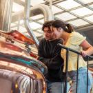 Students lean over large brewing kettle