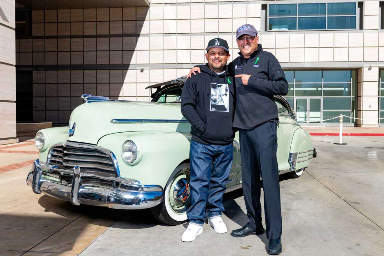 Louie Mejia smiling in front of classic car