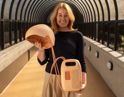 Woman standing in a tunnel holding a medical device consisting of a helmet and battery powered controller