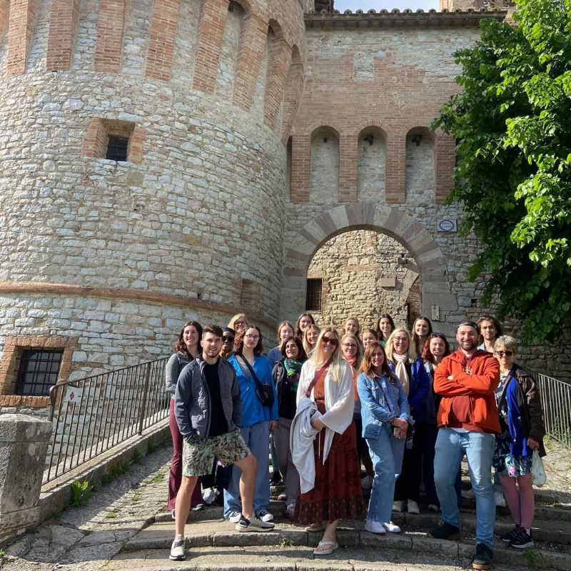 group of students standing and smiling for a picture in front of a castle