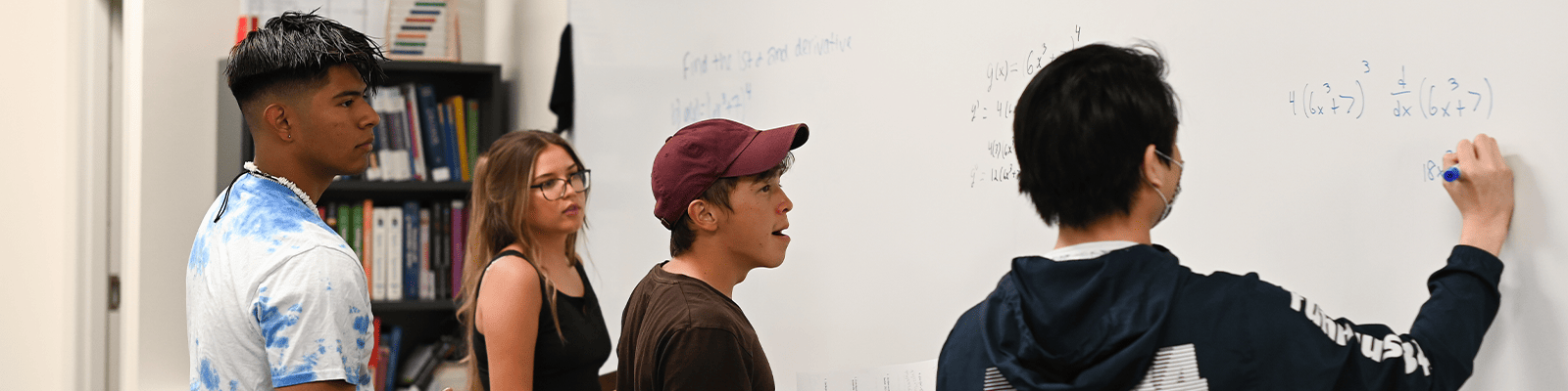 Students writing on a whiteboard to their right