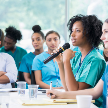 student holding a microphone as others listen