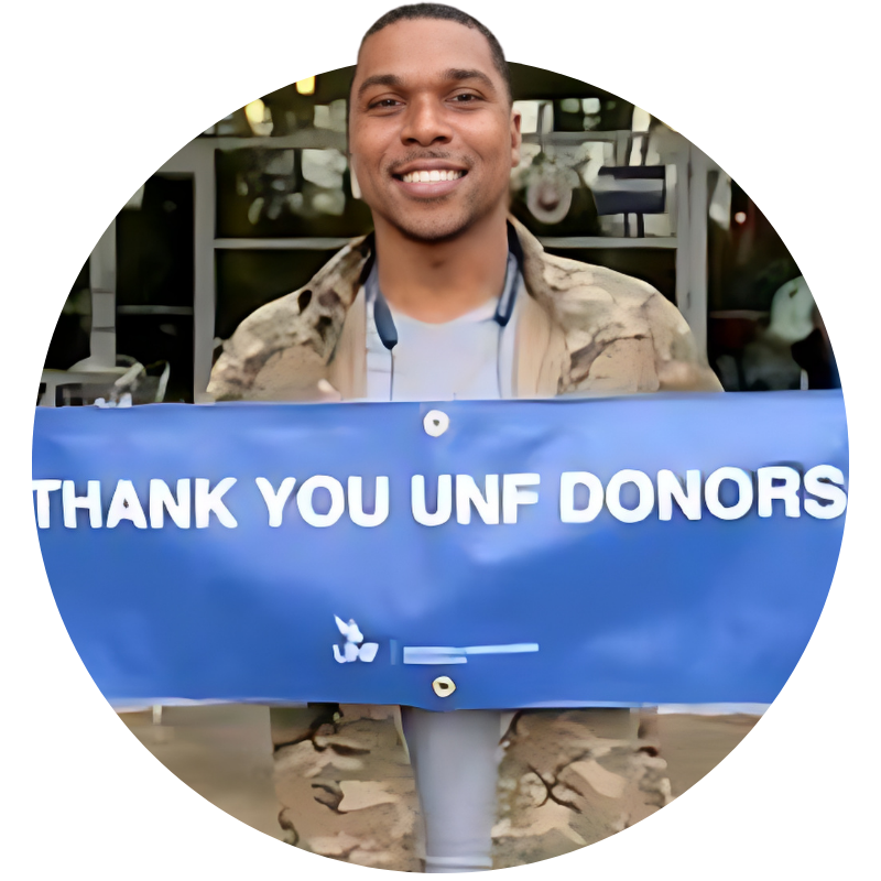 man holding a sign that says thank you UNF donors