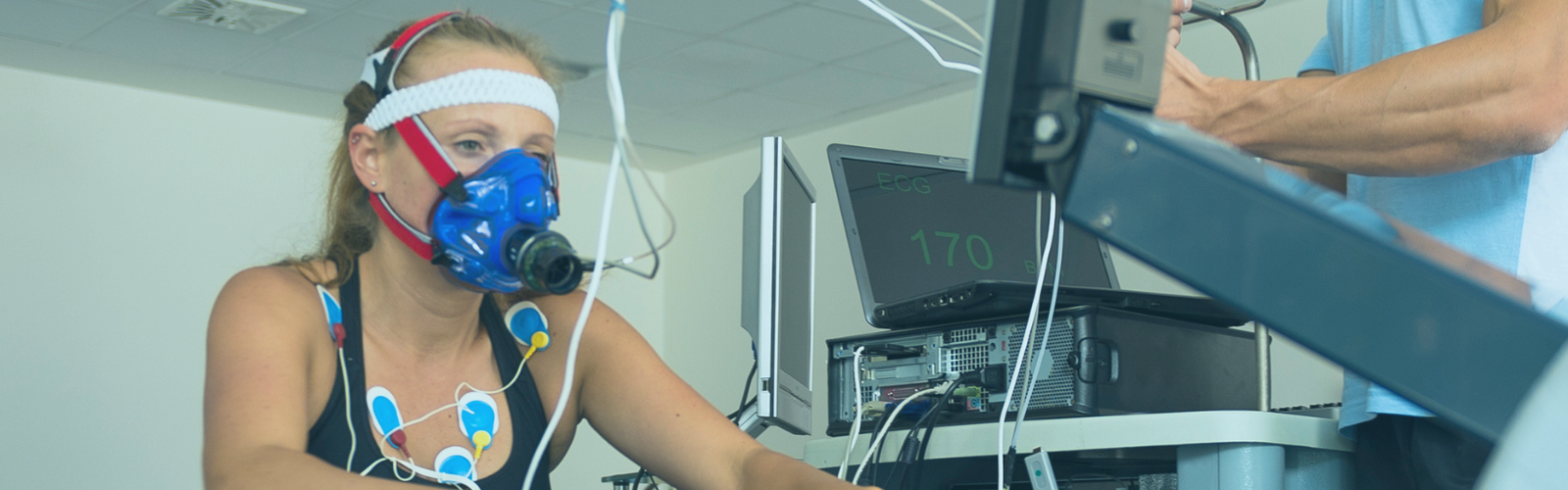 women on a bike wearing a v02max mask and heart rate monitor stickers on her body