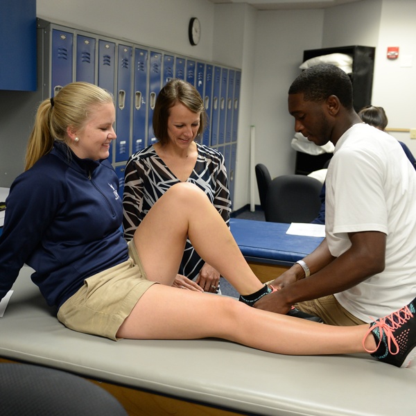 students working on each other under the guidance of an instructor