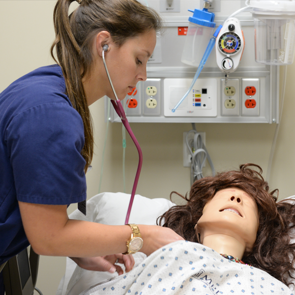 student checking for a heartbeat on a mannequin