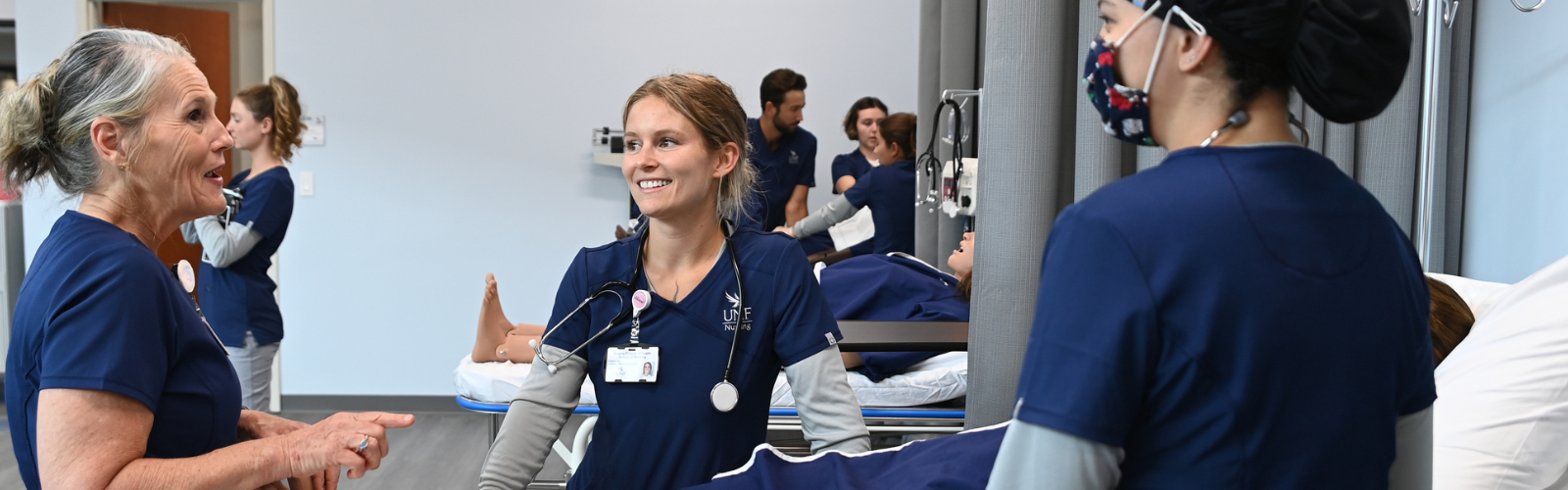 Two nursing students and one nursing faculty talking near a cadaver