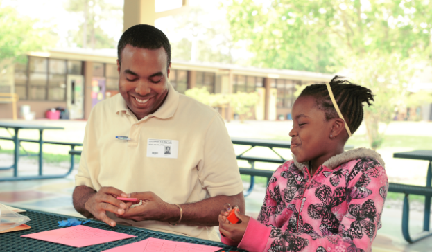 A student and a teacher sitting at a table and sharing a laugh