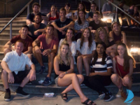 19 people sitting on stair steps with railings on either side