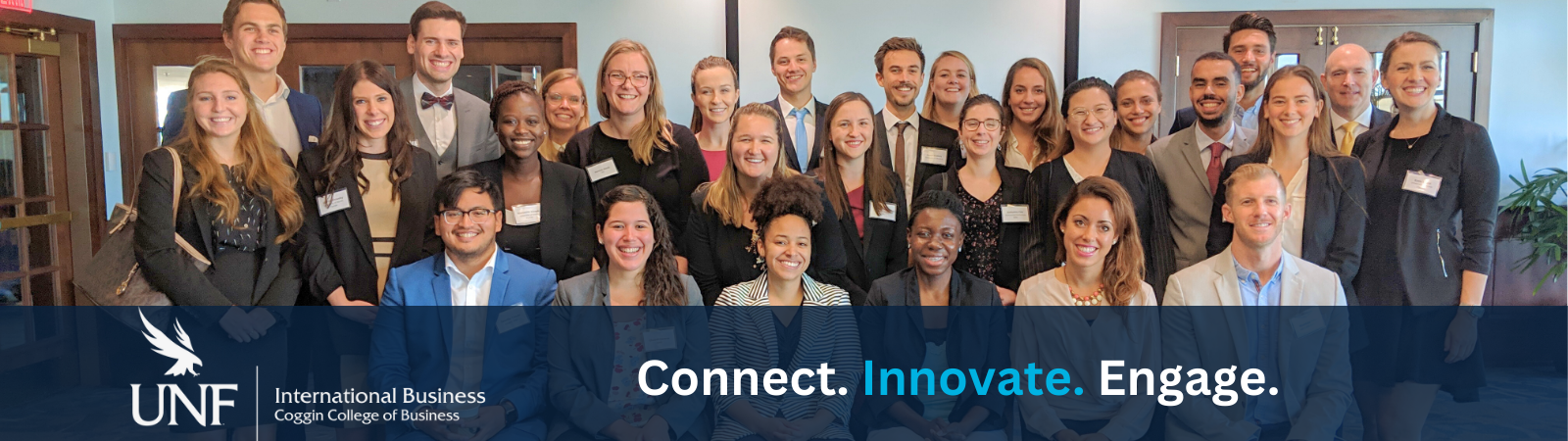 group of GlobalMBA students in professional dress smiling in a conference room