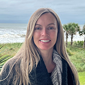 Headshot photo of Dr. Heather Truelove standing outside with the ocean in the background.