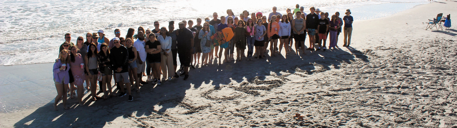 Group photo at beach with ocean behind. 