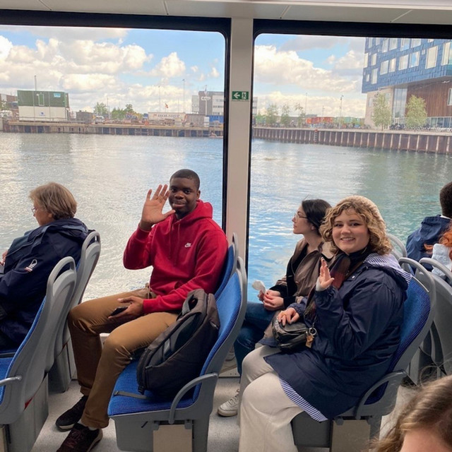 Students sitting in a vehicle with large windows overlooking water.