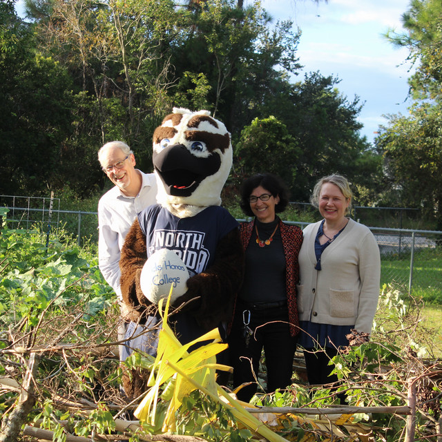 faculty pose with Ozzie in a giant nest made of sticks